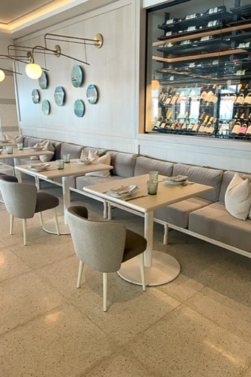 The spacious well-lit cafe has fixed padded bench seating and small square tables for two with moveable chairs.