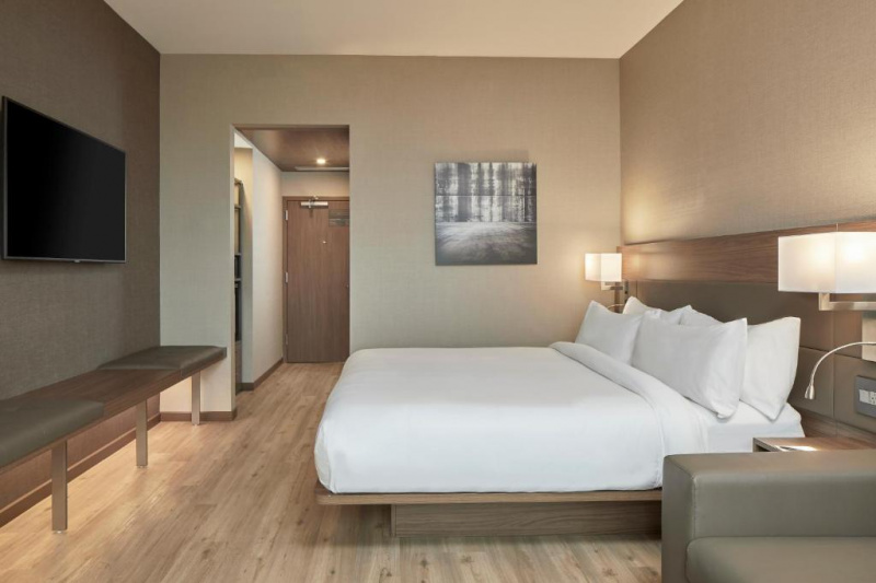 The 1 king guest room has an extra-large double bed, nightstands with wall mounted lamps, a wall-mounted flat-screen TV with a padded bench under.