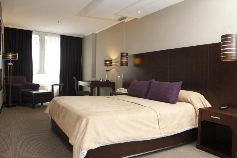 The superior double room has a large double bed, two nightstands, a telephone, hanging lamps, a desk, a chair and a table lamp. There is also a comfortable armchair, a footstool and a small table.