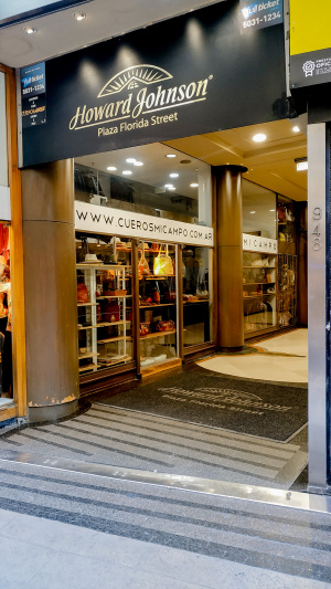The well-lit accessible hotel entrance is in a shop arcade.