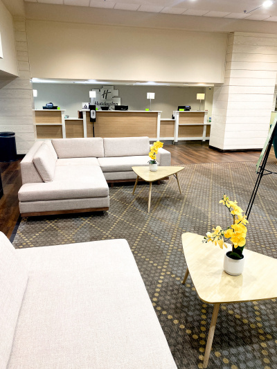 The lobby area has the reception desks which have lowered sections. There is a large L-shaped sofa with a coffee table. There is also another sofa and coffee table just out of shot.