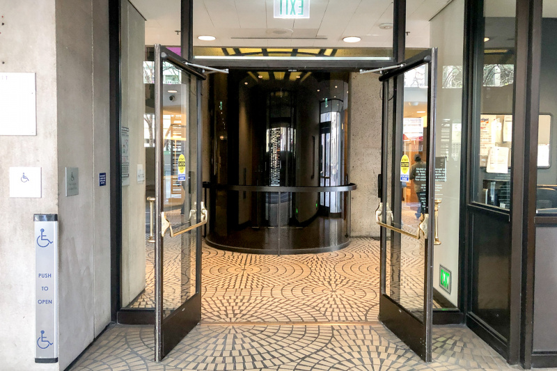 The accessible hotel entrance has a push button mechanism to open the automatic glass doors.