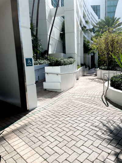 There is an accessible ramp with handrails. The ramp is brick paved and lined with shrub and flower borders.