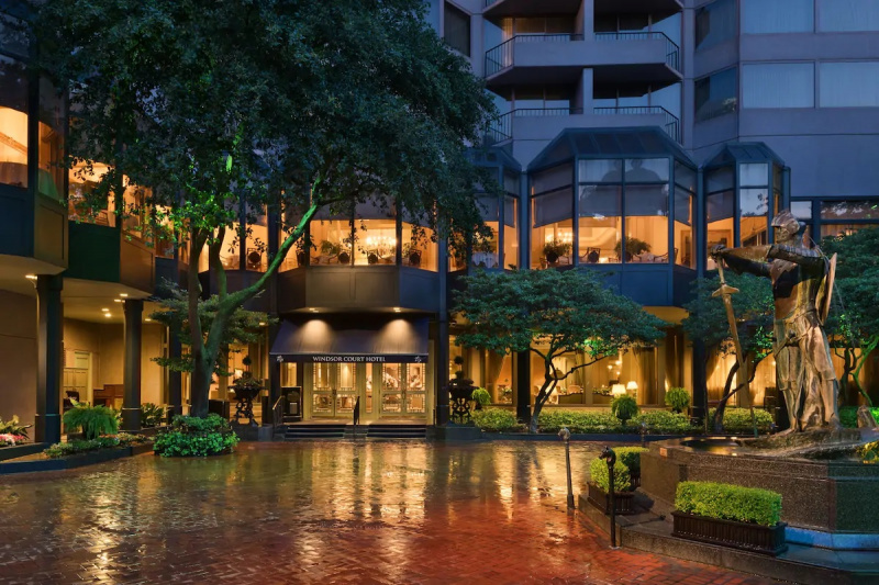 The wide, drive-up, hotel entrance has 3 small steps leading up to 2 sets of glass doors. The steps have handrails.