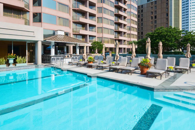 The 4-lane, outdoor pool has handrails leading to the water. There are loungers and tables around the poolside. There is also a bar with a high counter and bar stools.