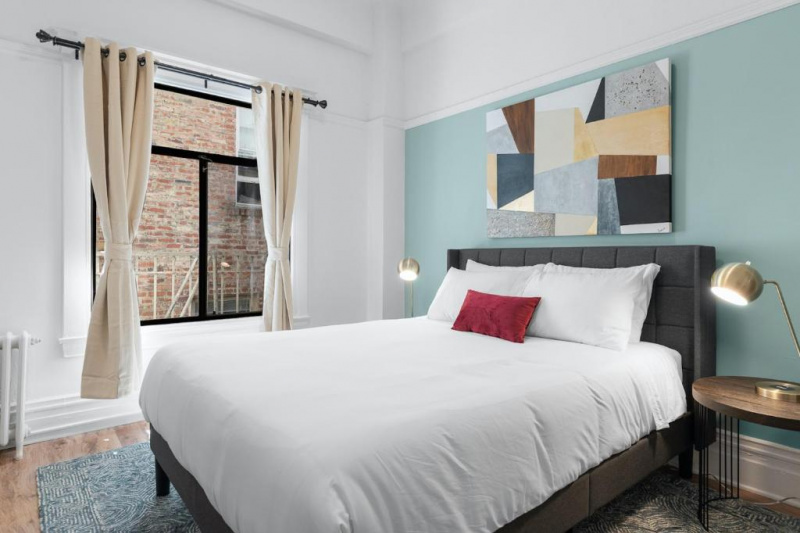 The superior suite bedroom has a king-sized bed. There are nightstands on either side of it, with table lamps on top. At the bottom of the bed is a bed bench. Opposite the bed is a desk and chair. The room is spacious and carpeted.