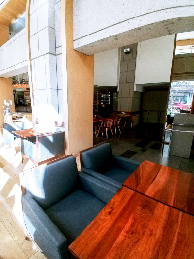 The seating area has 2 tables and chairs pushed together.There is more seating further into the room.