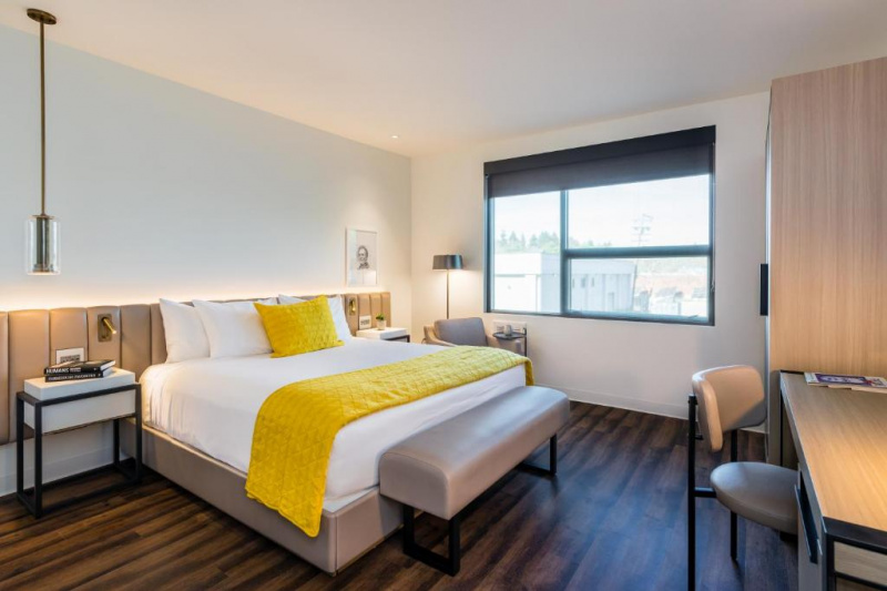 The king room has a king-sized bed with a plush bed bench at the end. There are nightstands on either side. Opposite the bed is a desk and chair and a wardrobe.