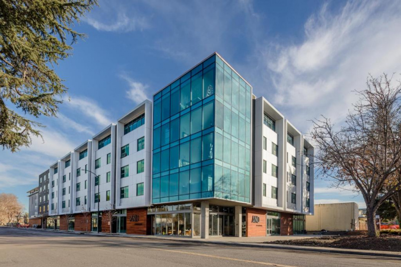 The 4 story hotel has a glass entrance from the sidewalk.