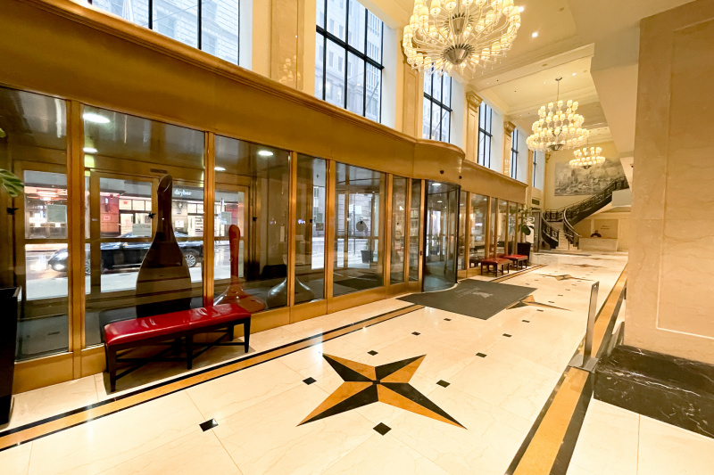 The hotel entrance has a revolving door. The lobby is large and step-free. There is a flight of stairs at the end of the room.