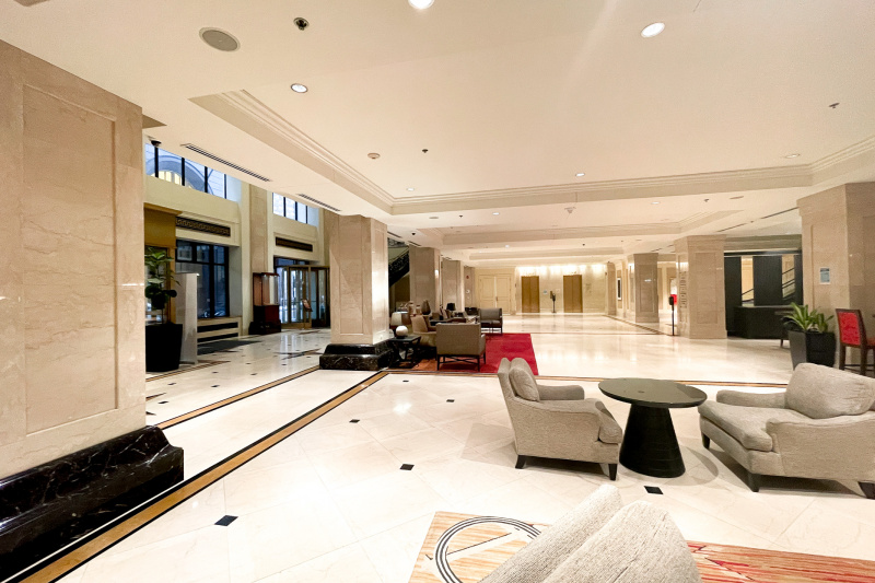 The spacious hotel lobby has assorted tables and chairs. There is plenty of space between the seats.