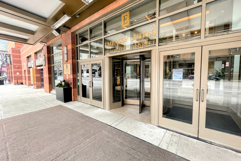 Close-up view of the hotel entrance and canopy. There is step-free access through a revolving door or through push-button automatic double glass doors on either side.