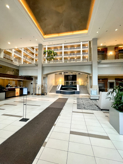 The spacious lobby has a comfortable seating area to one side with large plush armchairs. The check-in desk opposite has a low shelf and dropped counter area.