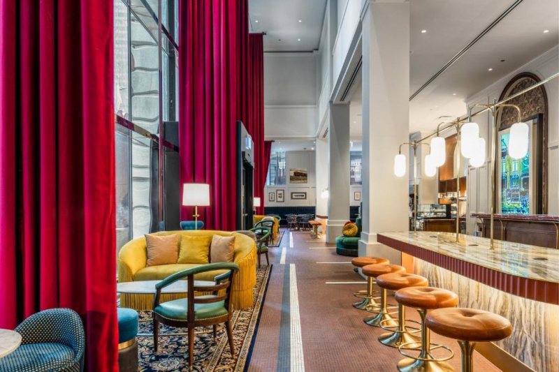 The accessible glass-fronted hotel lounge has several seating areas with sofas, plush stools, low tables and movable chairs. There is also a counter with bar stools and room to maneuver between seating areas.