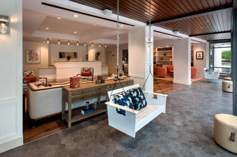The spacious hotel reception has several seating areas with assorted sofas, banquettes, chairs and swinging benches. The check-in desk has lowered counters at each end.