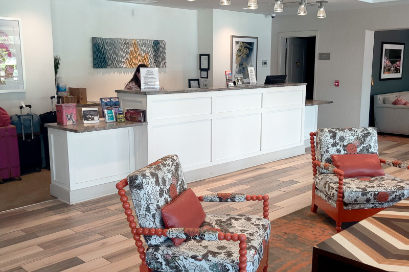 The accessible check-in desk has lowered counters at each end. There is a low table and two low armchairs in front of the desk.