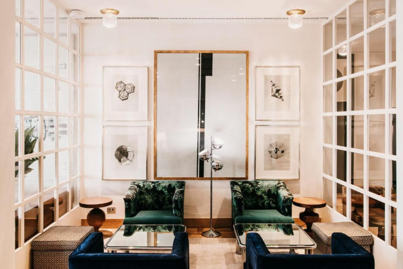 The small hotel seating area has comfortable low armchairs, ottoman stools and low tables. The area is well-lit with artwork on the walls, but little space to maneuver.