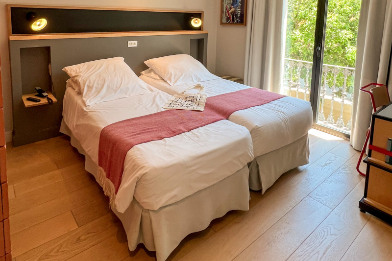 The twin room has 2 single beds pushed together. There is a built-in headboard with pulldown nightstands. Opposite the bed is a desk and chair.