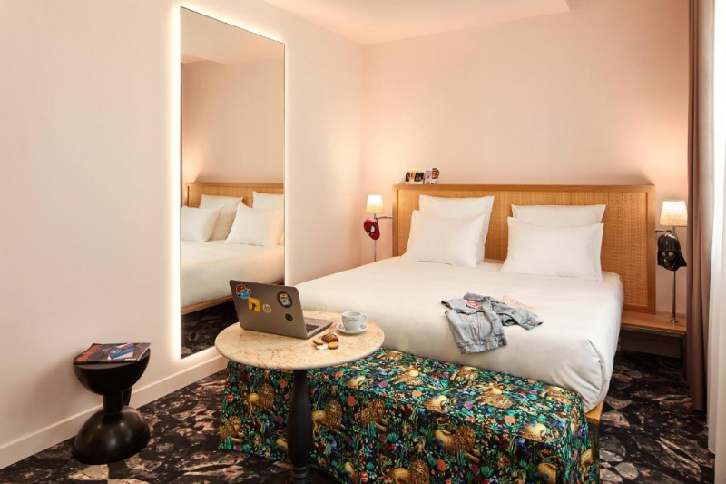 This room has a double bed with nightstands and reading lamps. There is a bed bench at the foot of the bed with a coffee table. There is also a full-length mirror to one side of the bed.