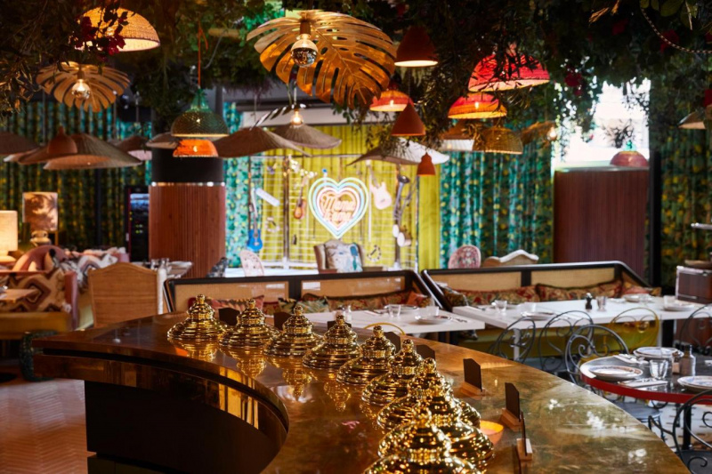 The standard height food counter in the dining area is curved, with a copper-colored countertop. There are metal food covers on the counter.