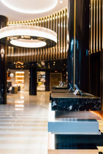 There are 3 sets of standard height reception desks in a large step-free area.
