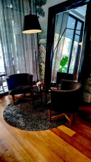 The seating area has 2 armchairs and a small coffee table on a round rug. There is a full length mirror behind them.