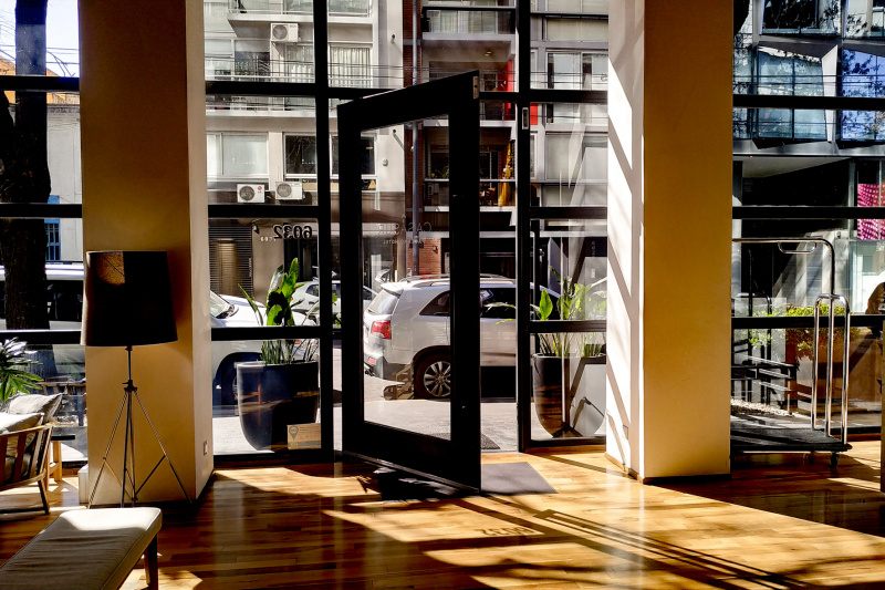 The hotel lobby leads out onto the sidewalk through a large glass door.