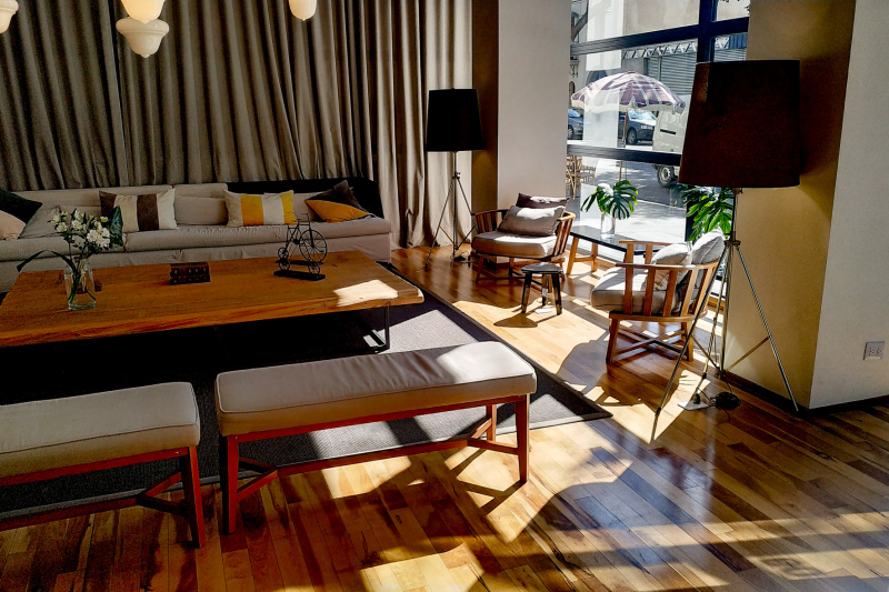 The spacious seating area has a long sofa along one wall. There is also a large coffee table, 2 padded benches, and 2 armchairs.