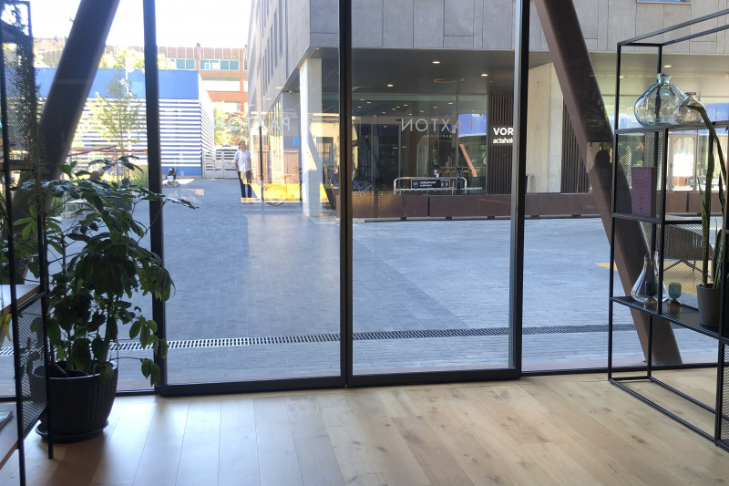 The step-free hotel exit is through double glass doors leading onto a large, paved pedestrian area.