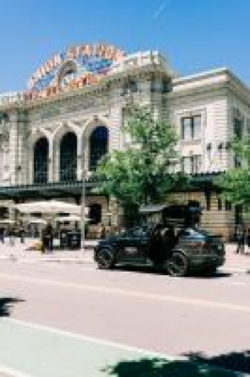 The hotel is a converted train station. It is on a very wide street and its entrance is from the sidewalk.