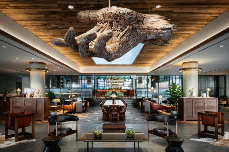 The lobby has a high reception desk and assorted tables and movable chairs. There are 4 stairs with handrails leading to the bar area.