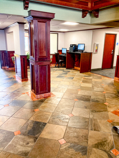 There are 2 workstations to the side of a spacious, step-free area. One computer is on an accessible counter, the other on a lowered counter with a chair.