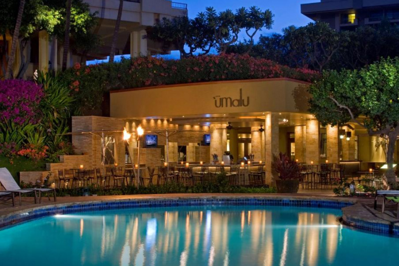 At the far end of the outdoor pool there is a bar with assorted tables and chairs. Round the narrow poolside there are loungers.