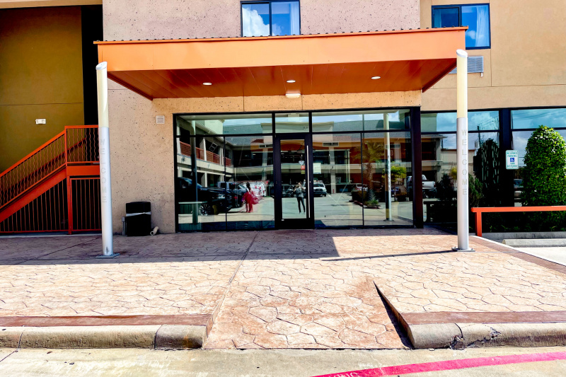 A cobbled area leads to the hotel entrance. There is a ramp leading to the single, glass hotel doorway.