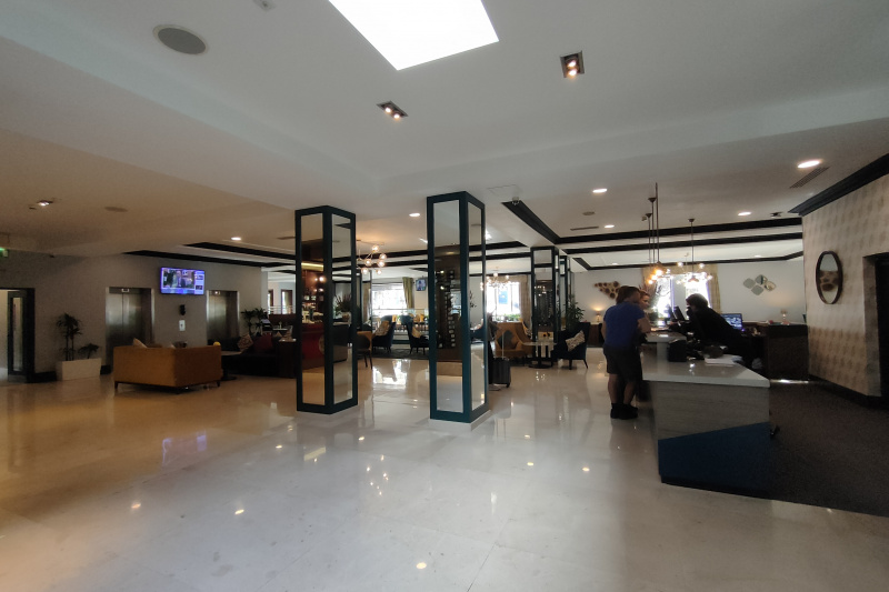The spacious, step-free reception area has a high check-in desk with a lower counter area. there are assorted tables and chairs and 2 elevators.
