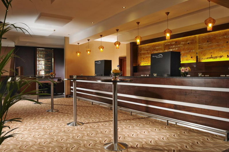 The bar counter is high with high tables lining the room. There is ample floor space in the carpeted room.