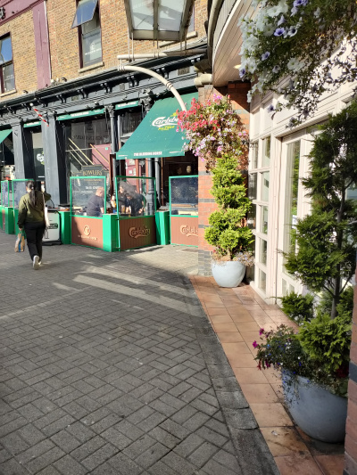 The sidewalk is step-free and paved. There is a set of white next to a pub.