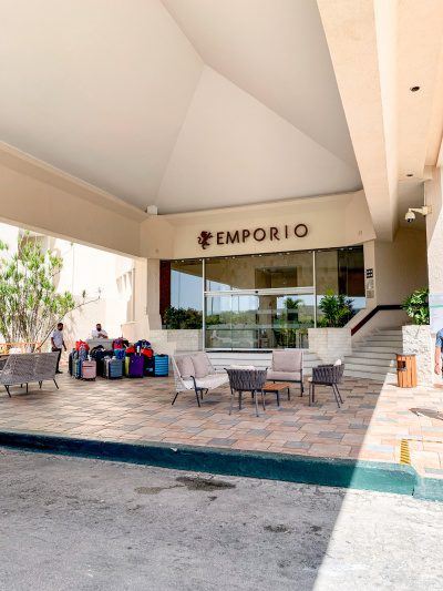 Access to the hotel is from the sidewalk, which has tables and chairs. There are 3 steps leading to a set of automatic glass sliding doors. To the right is a flight of steps leading to the next floor.