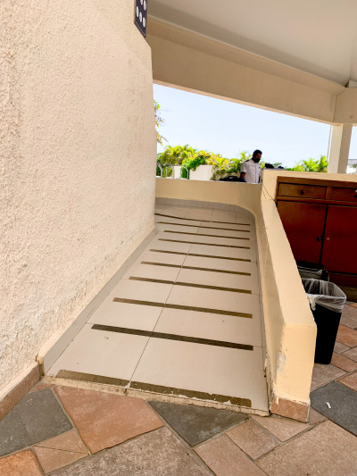 There is a wide ramp wiith anti-slip stripes leading to the hotel entrance round the corner. There are no handrails