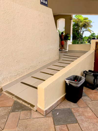 There is a wide ramp with anti-slip stripes leading to the hotel entrance around the corner. There are no handrails.