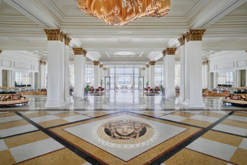 The spacious lobby has massive columns. There are steps with handrails leading down to the hotel exit.