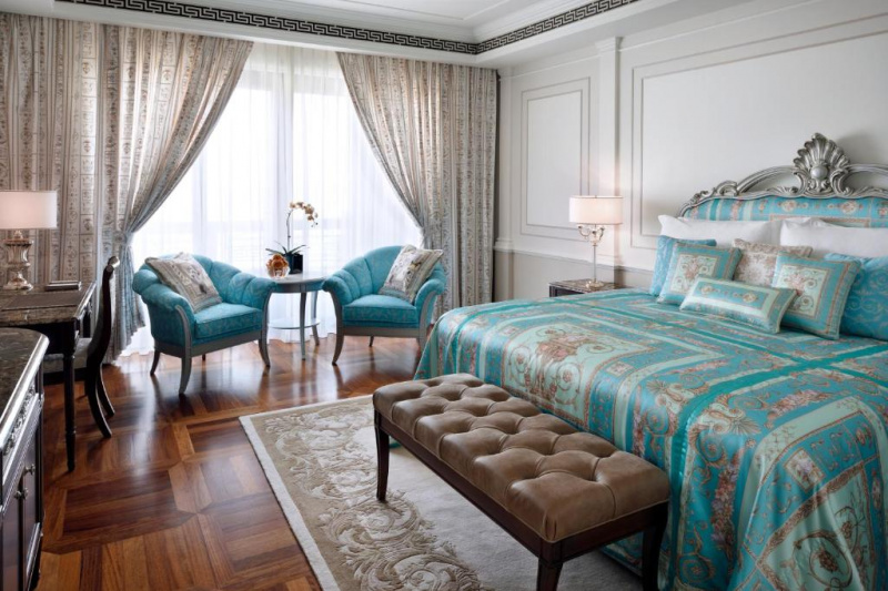 The spacious room has 1 king-sized bed with nightstands, a plush bed bench, 2 armchairs and a coffee table. Opposite the bed is a workstation and a movable chair.