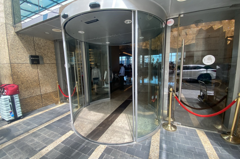 Access to the hotel entrance is through a revolving door with single glass doors on either side.
