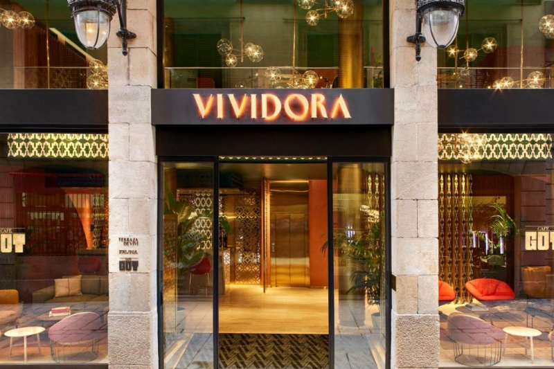 Access to the hotel entrance is through tall, glass automatic doors. Inside, there is seating on either side of the entrance with a clear space in the middle.