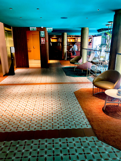 The spacious, step-free area has 2 elevators on one side. There are 2 sets of coffee tables and chairs on the other side.