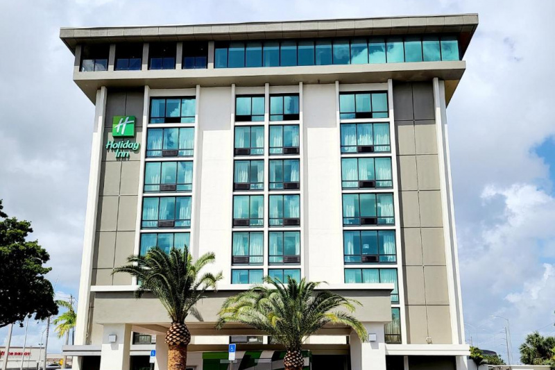 An exterior view of the standalone hotel with prominent hotel name sign.