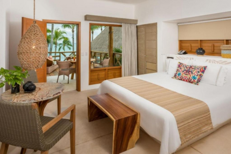 The hotel room has 1 king-sized bed with a wooden bed bench. There is also a coffee table and 2 chairs and a door leading to the furnished terrace. Floor space is limited.