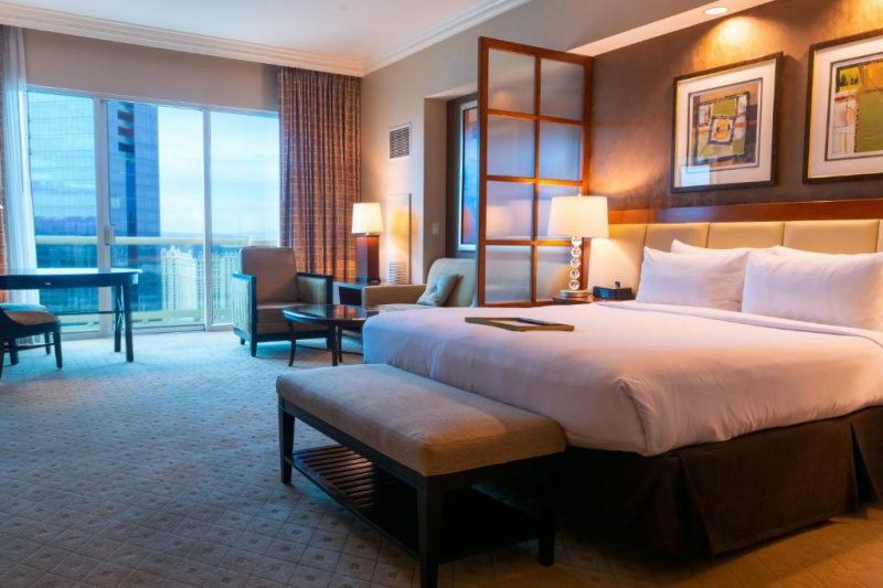 The spacious carpeted suite has a king-sized bed with nightstands and plush bench. The separate seating area has a queen-sized sofa-bed, armchair and coffee tables and a dining table and chair.