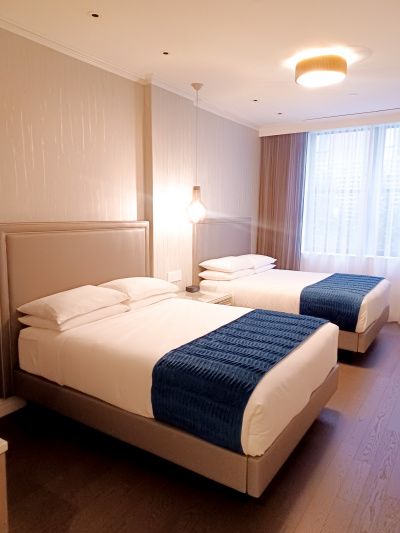 The 2 queen-sized beds have a nightstand between them.