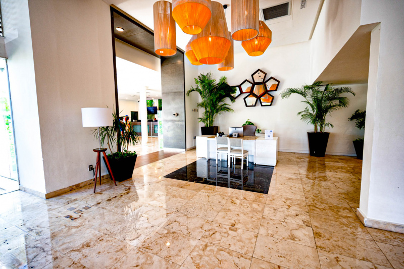 The reception desk is in a large, step-free area. The reception desk is low and has 2 chairs in front of it.